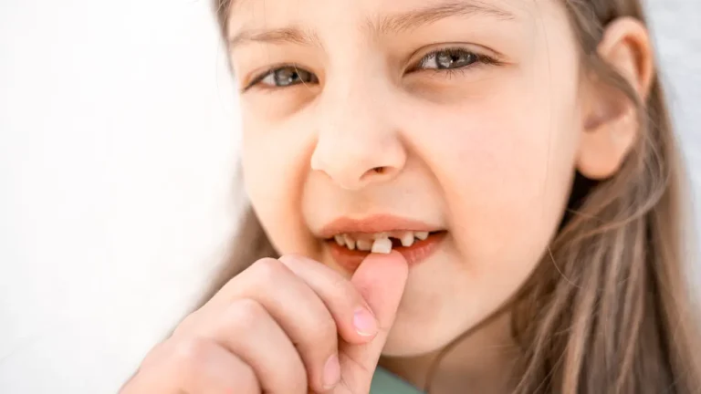 Child touching loose baby tooth while checking it