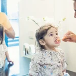 Father helping young child brush teeth before dental visit