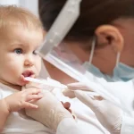 Infant receiving early dental checkup with parent nearby