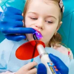 Child receiving dental sealant treatment with curing light